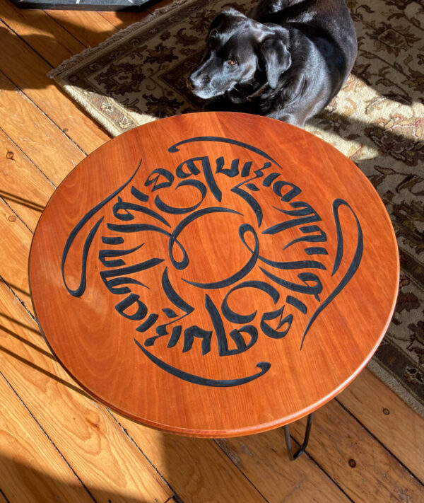 A cherry side table carved with the phrase “graceful kindness” in Tibetan